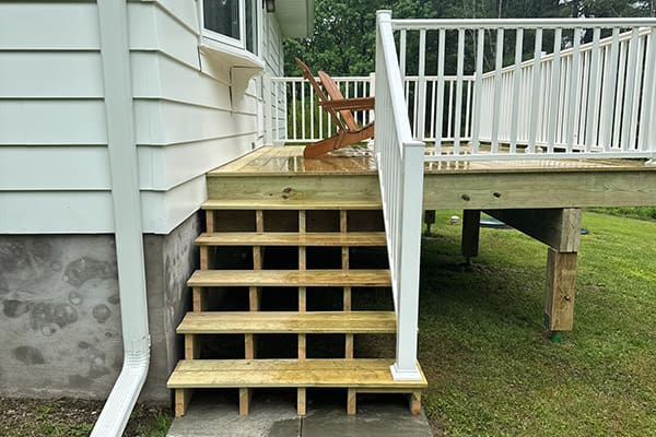 A wood deck installation with white vinyl railing